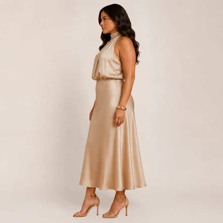Female model in a beige halter dress styled for formal events on a plain background.