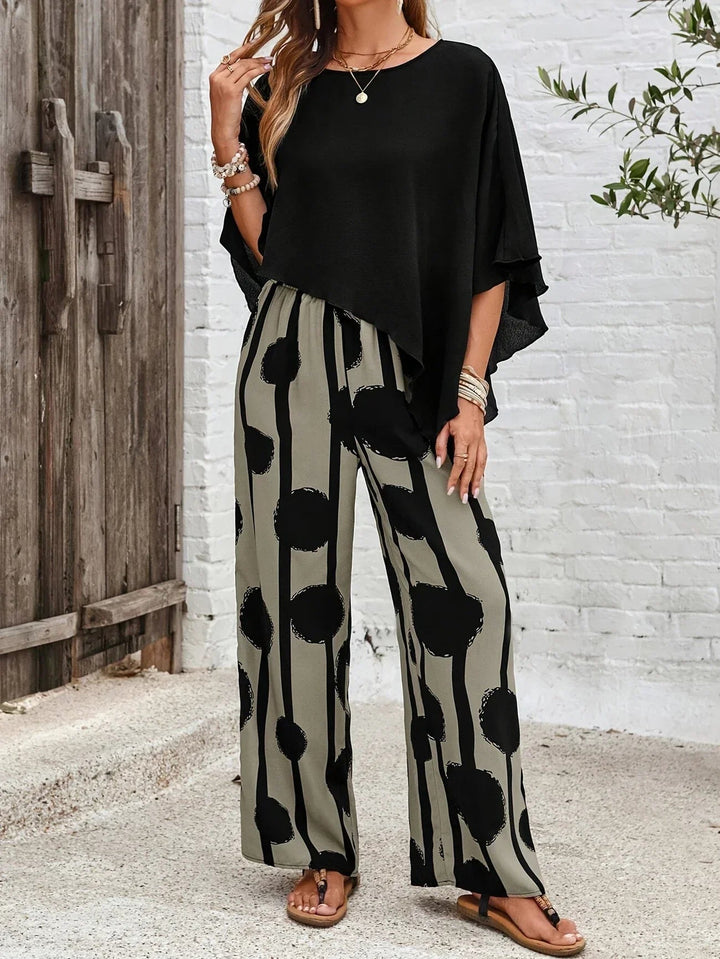 Female model showing a casual matching set with asymmetric top and printed trousers.