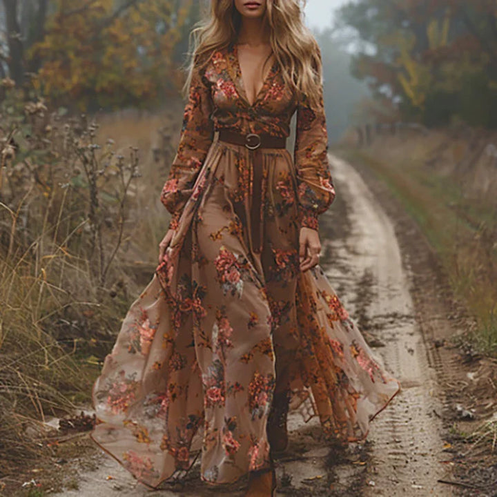 Woman in a floral print dress with a defined waist and elegant styling on a plain background.
