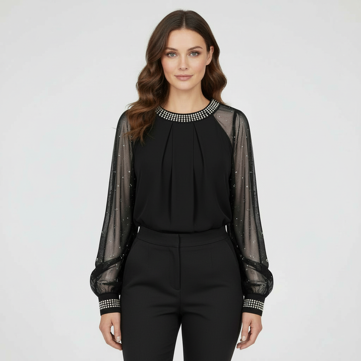 Woman wearing a sheer mesh sequin top with long sleeves against a plain background.