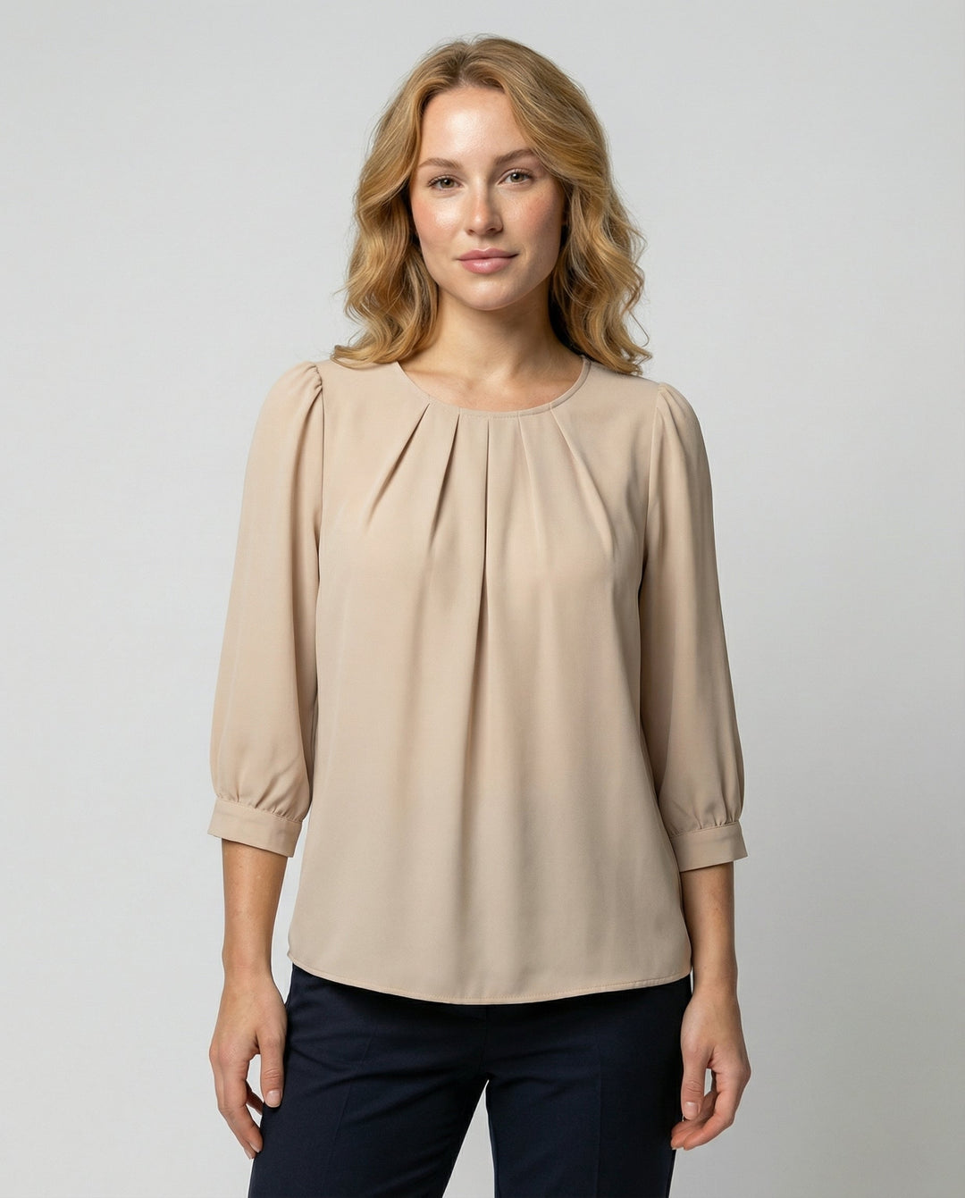 Woman wearing a satin blouse with pleated detailing against a plain background.