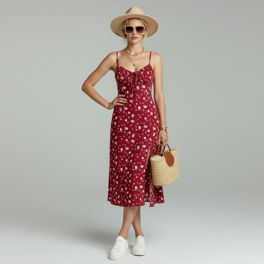 Woman wearing a floral midi dress with spaghetti straps against a plain background.