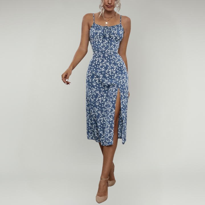Woman showcasing a floral midi dress with slim straps and side slit against a plain background.