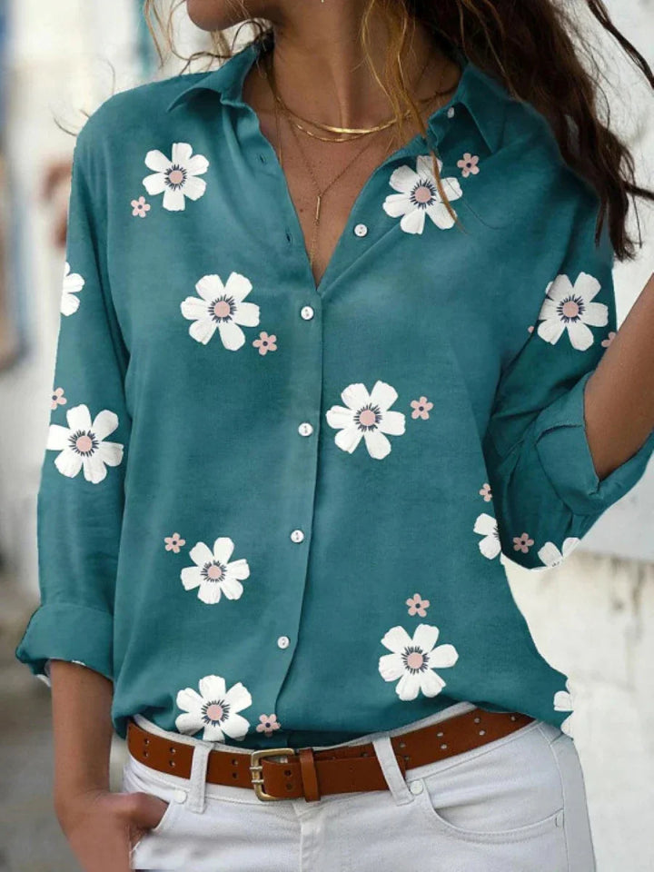 Woman wearing a floral print button-front blouse against a plain background.