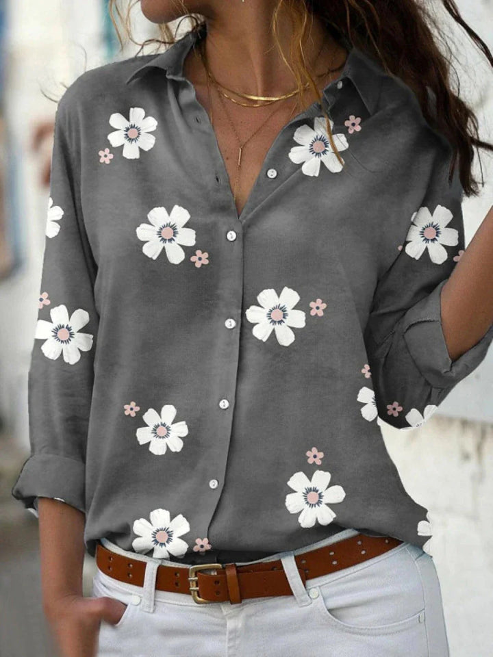  Woman in a floral print blouse with a relaxed silhouette on a plain background.