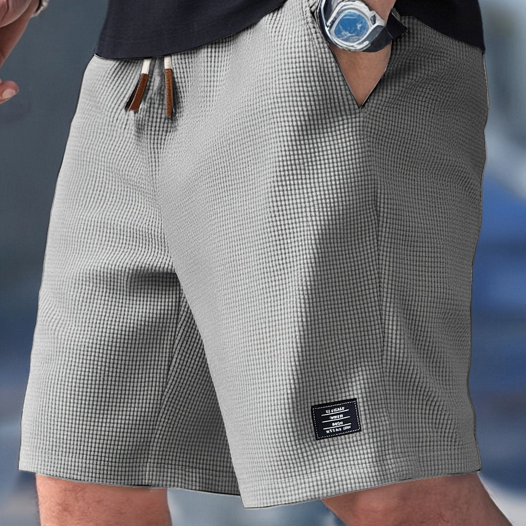 Male model wearing relaxed drawstring shorts for daily wear on a plain background.