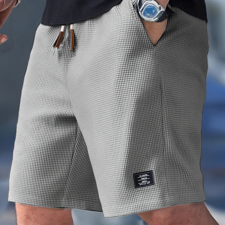 Male model wearing relaxed drawstring shorts for daily wear on a plain background.