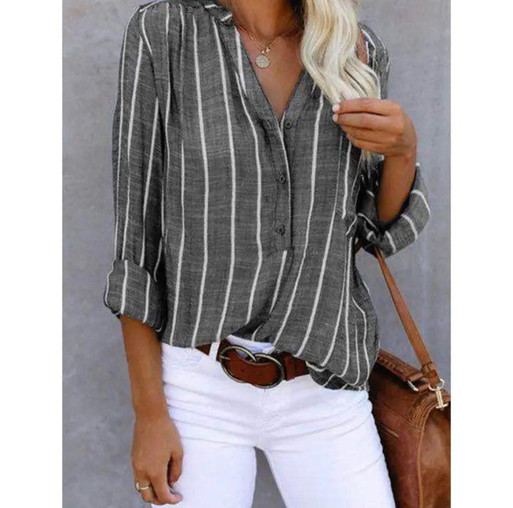  Woman wearing a versatile striped blouse on a plain background.