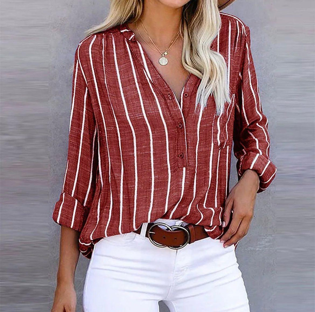 Woman wearing a striped casual blouse with roll-up sleeves against a plain background.