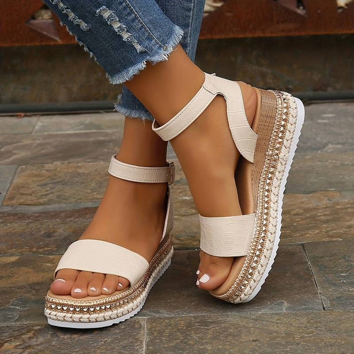 Female model wearing raised sole sandals on a plain background.