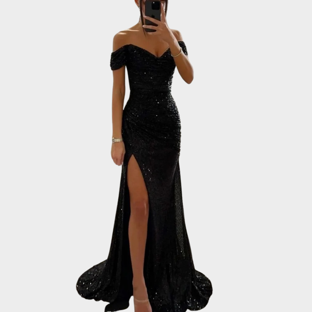 Woman in a fitted sequin evening dress with an open shoulder design on a plain background.