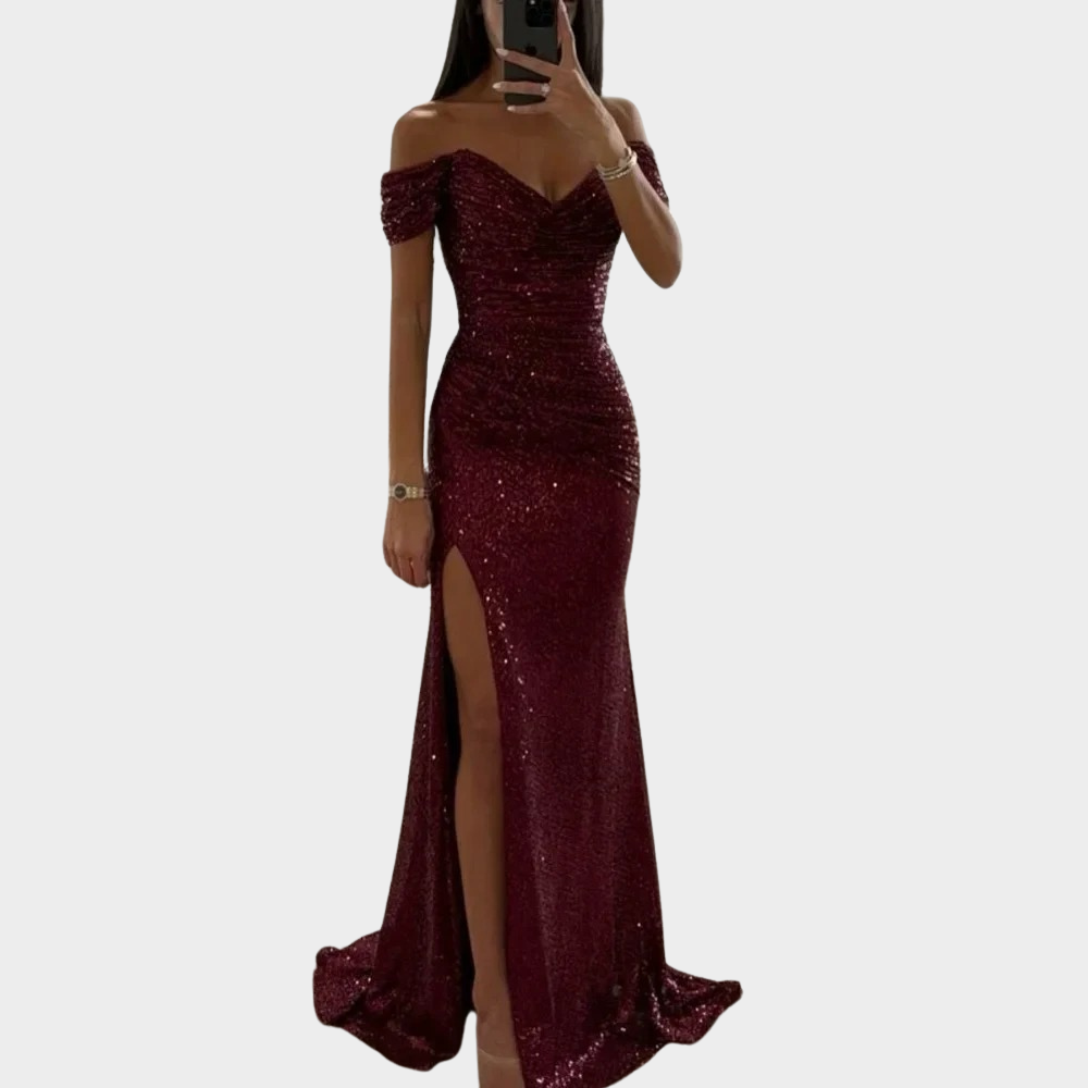 Model wearing a formal evening dress with subtle sparkle and front slit on a plain background.