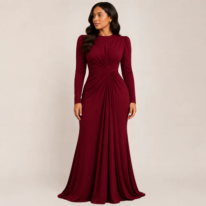 Woman posing in a fitted evening dress with long sleeves on a plain background.