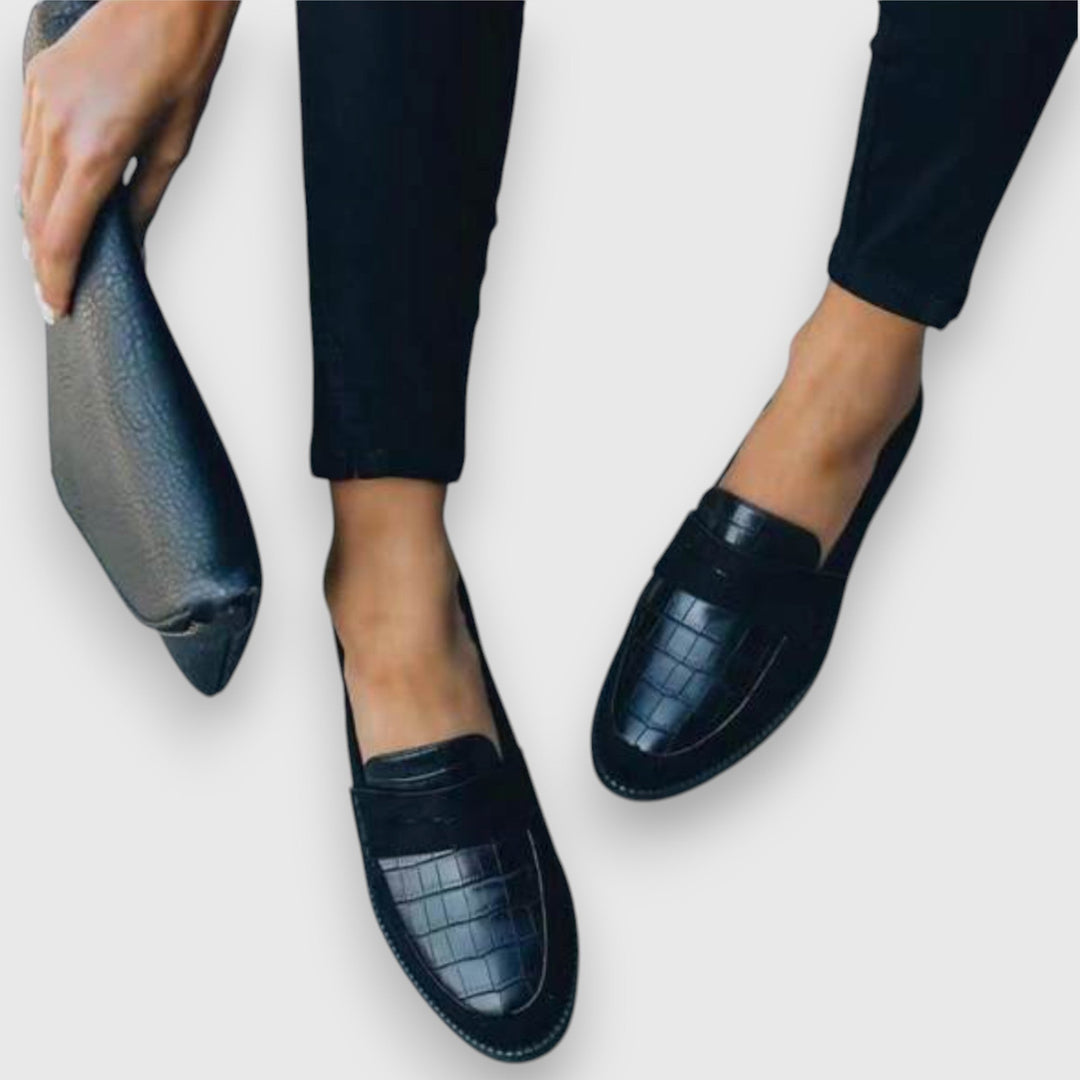 Woman standing in polished everyday loafers on a plain background.
