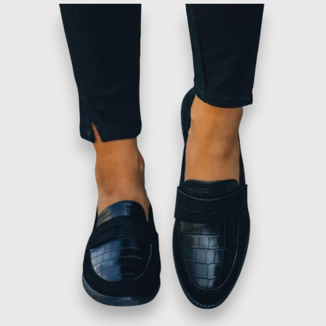Female model wearing classic slip-on shoes on a plain background.