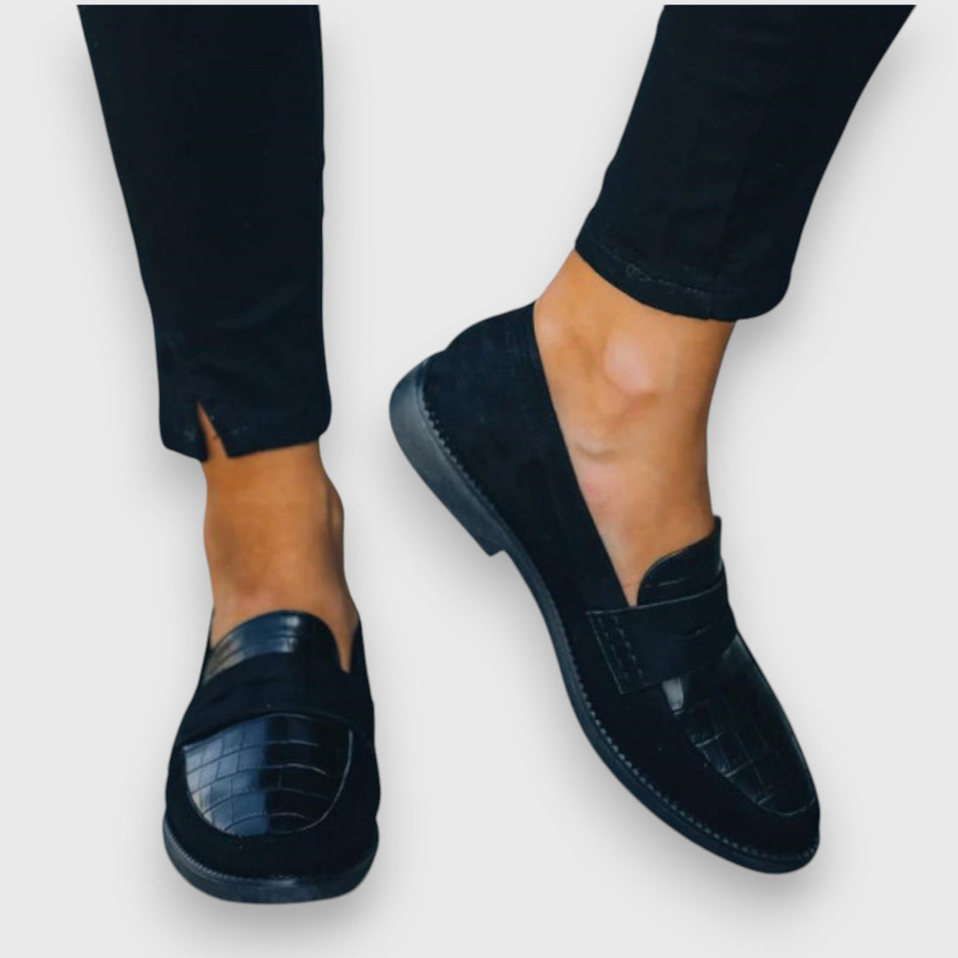 Female model showcasing smart casual loafers on a plain background.