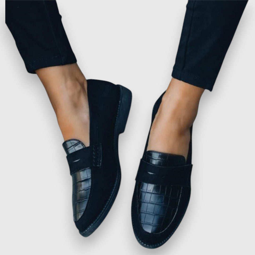 Woman wearing stylish slip-on loafers on a plain background.