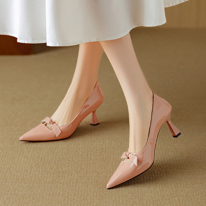 Bow detail pointed toe heel in blush tone on a plain background.