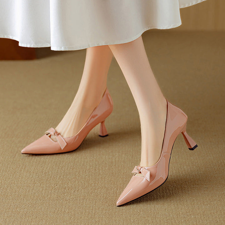 Bow detail pointed toe heel in blush tone on a plain background.