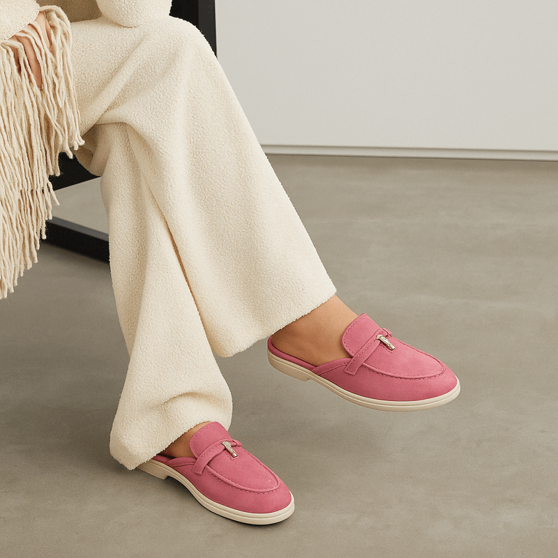 Female model wearing backless mule shoes on a plain background.