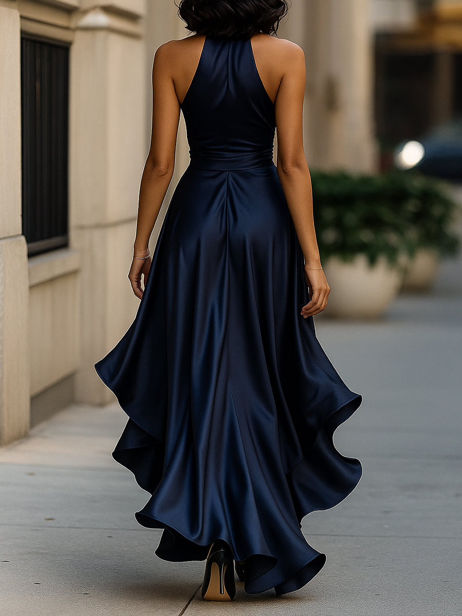Woman in a navy wrap waist gown with ruffle hem on a plain background.