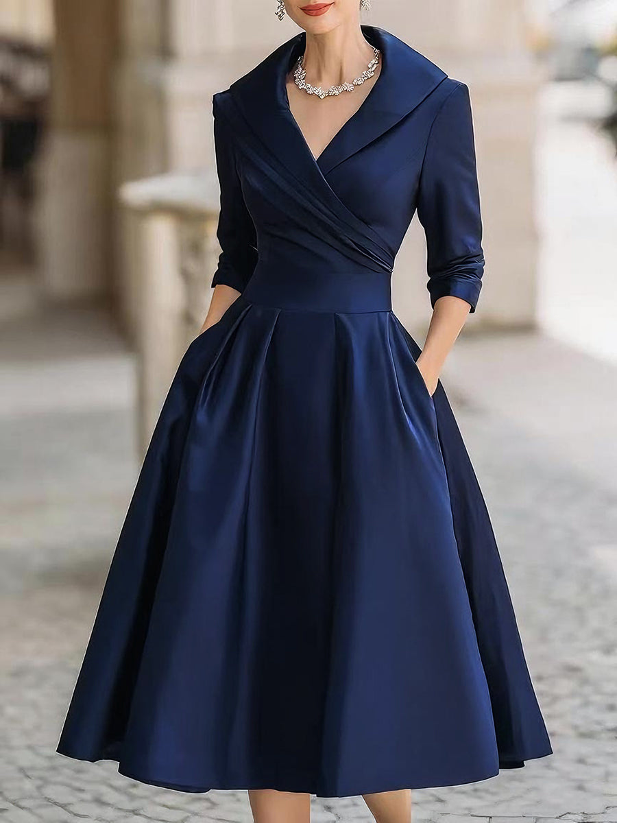 Model wearing an elegant long sleeve midi dress with soft neckline detail on a plain background.