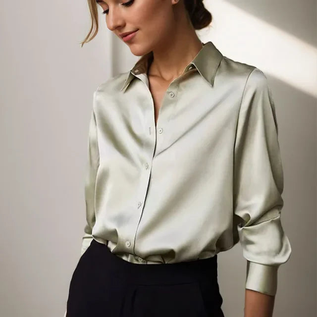 Female model wearing a satin button-down blouse with long sleeves against a plain background.