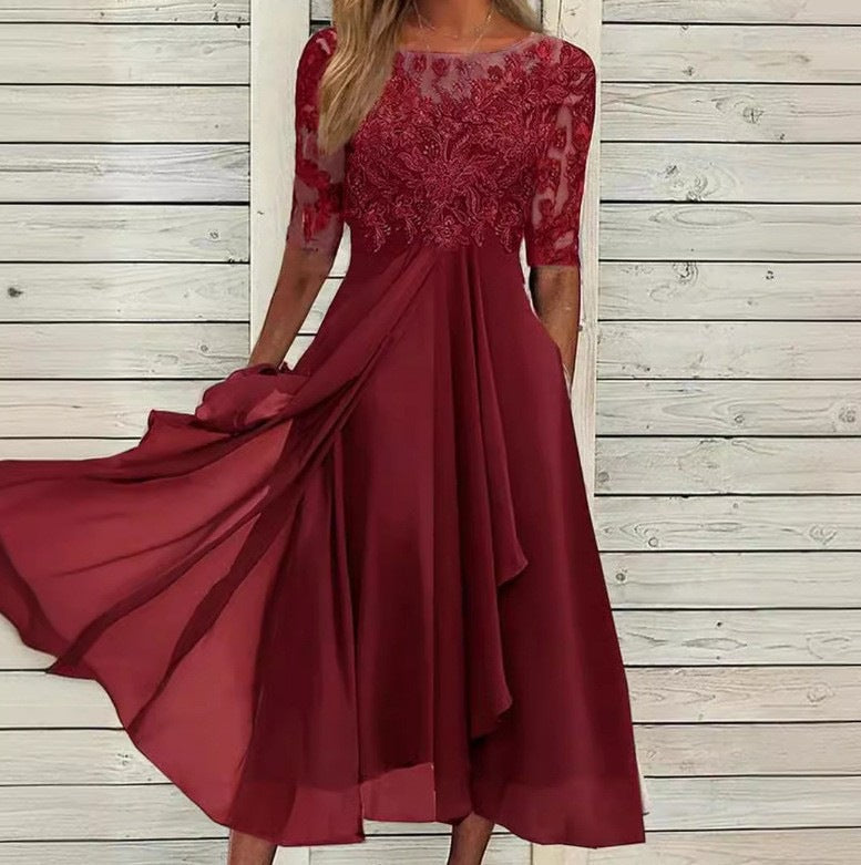 Woman wearing an ankle-length evening dress with lace bodice on a plain background.