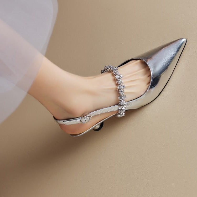 Female wearing pointed toe slingback heels with crystal strap against a plain background.