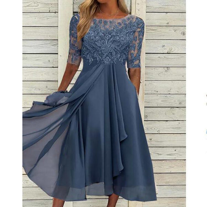 Woman wearing a bridesmaid-style dress with lace bodice on a plain background.