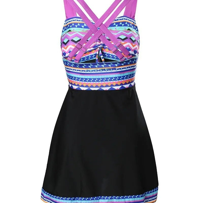 Model wearing a bold geometric swimwear dress with adjustable straps on a plain background.