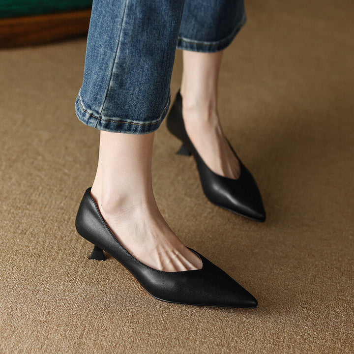 Woman wearing elegant nude low heel pumps on a plain background.