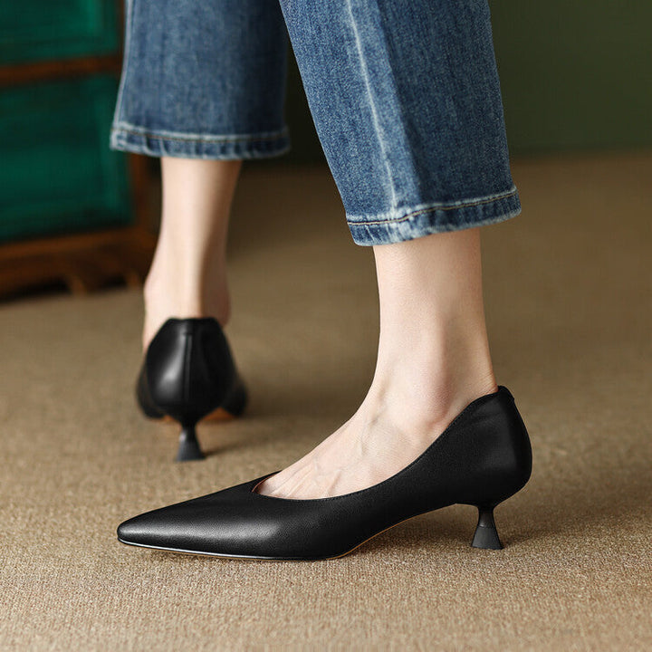 Female model wearing slip-on kitten heel dress shoes on a plain background.