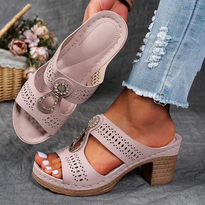 Female model standing in slip-on wedge sandals on a plain background.