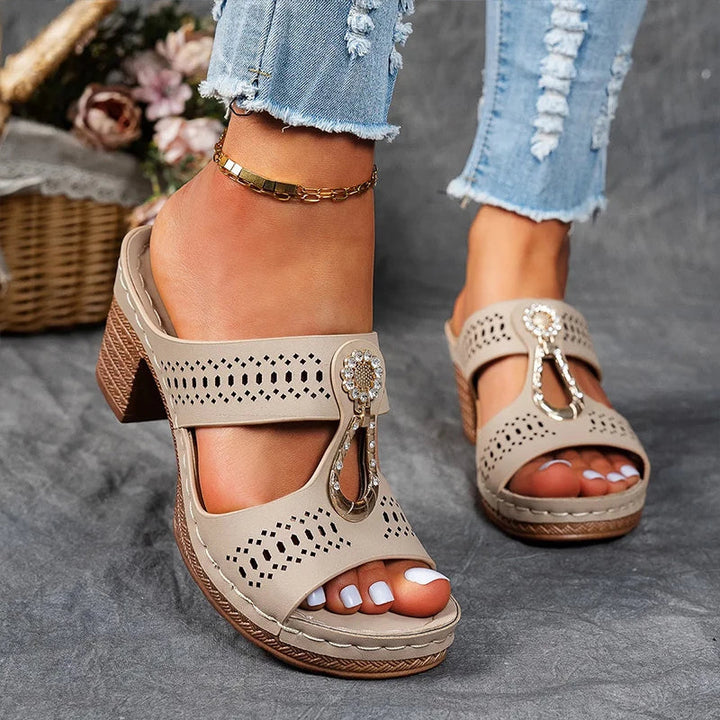 Woman showcasing open-toe wedge sandals on a plain background.