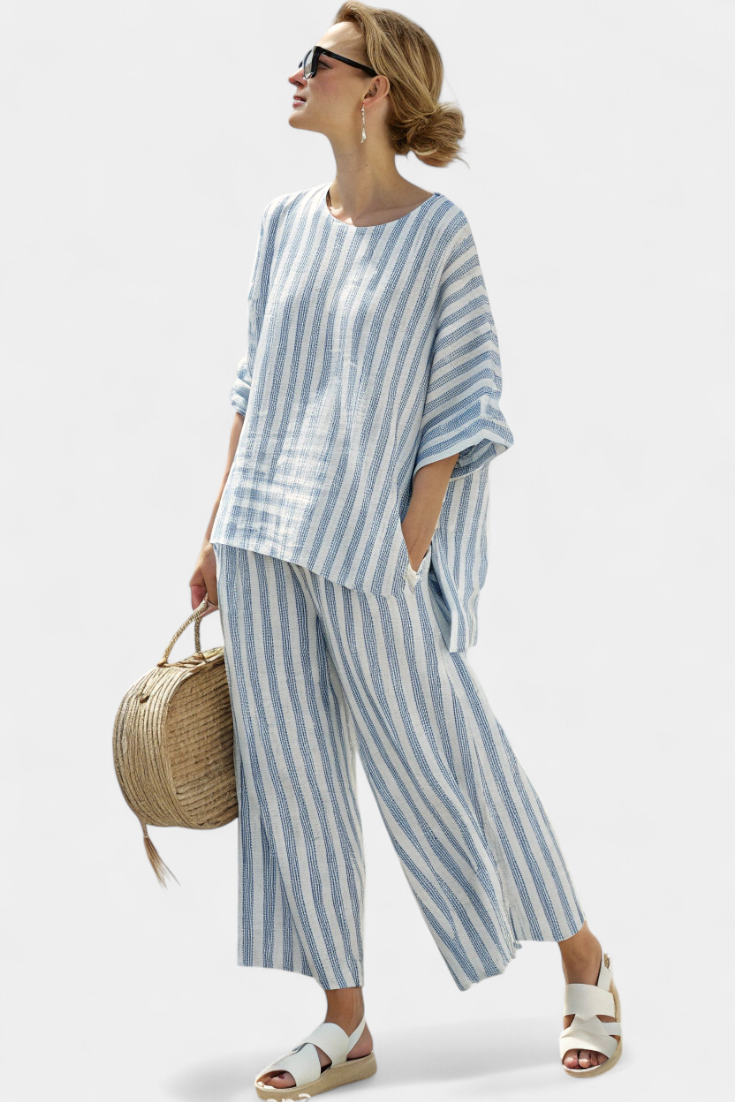 Female model wearing a blue and white striped two-piece outfit with wide leg cropped trousers on a plain background.