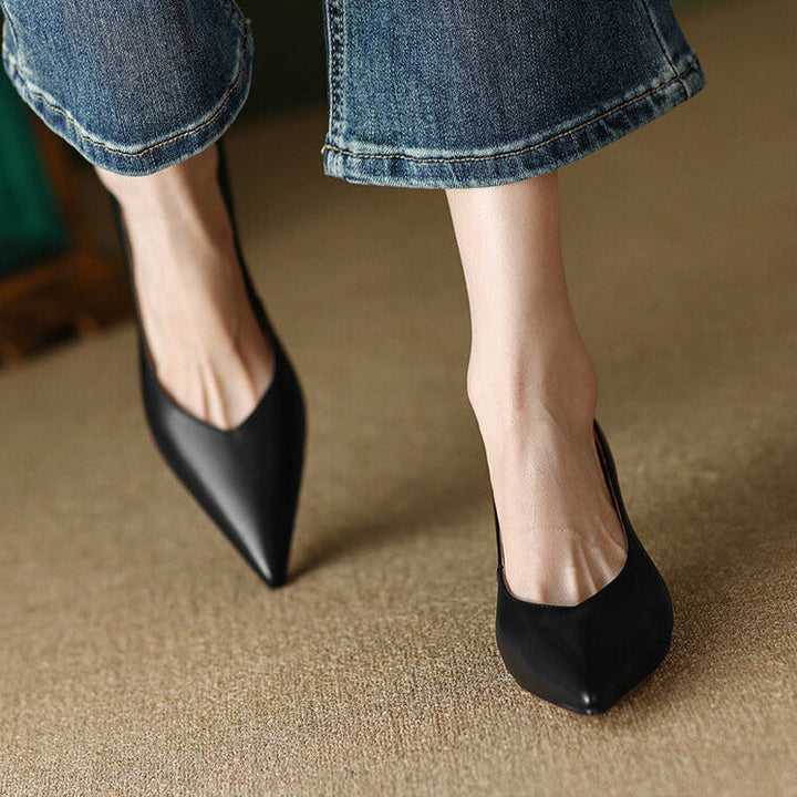 Woman in nude pointed toe pumps styled for smart outfits on a plain background.