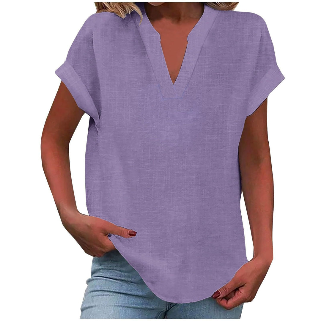 Woman wearing a relaxed-fit blouse with a notched neckline against a plain background.