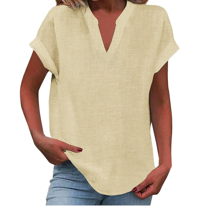 Woman wearing a draped blouse with rolled sleeves on a plain background.