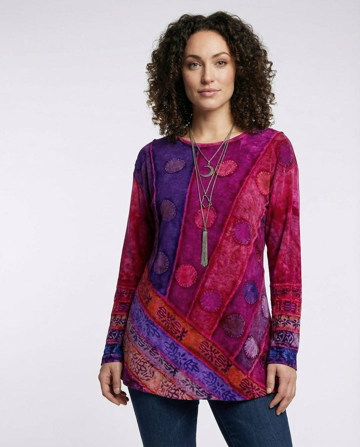Woman wearing a colourful vintage tunic with a patterned design against a plain background.