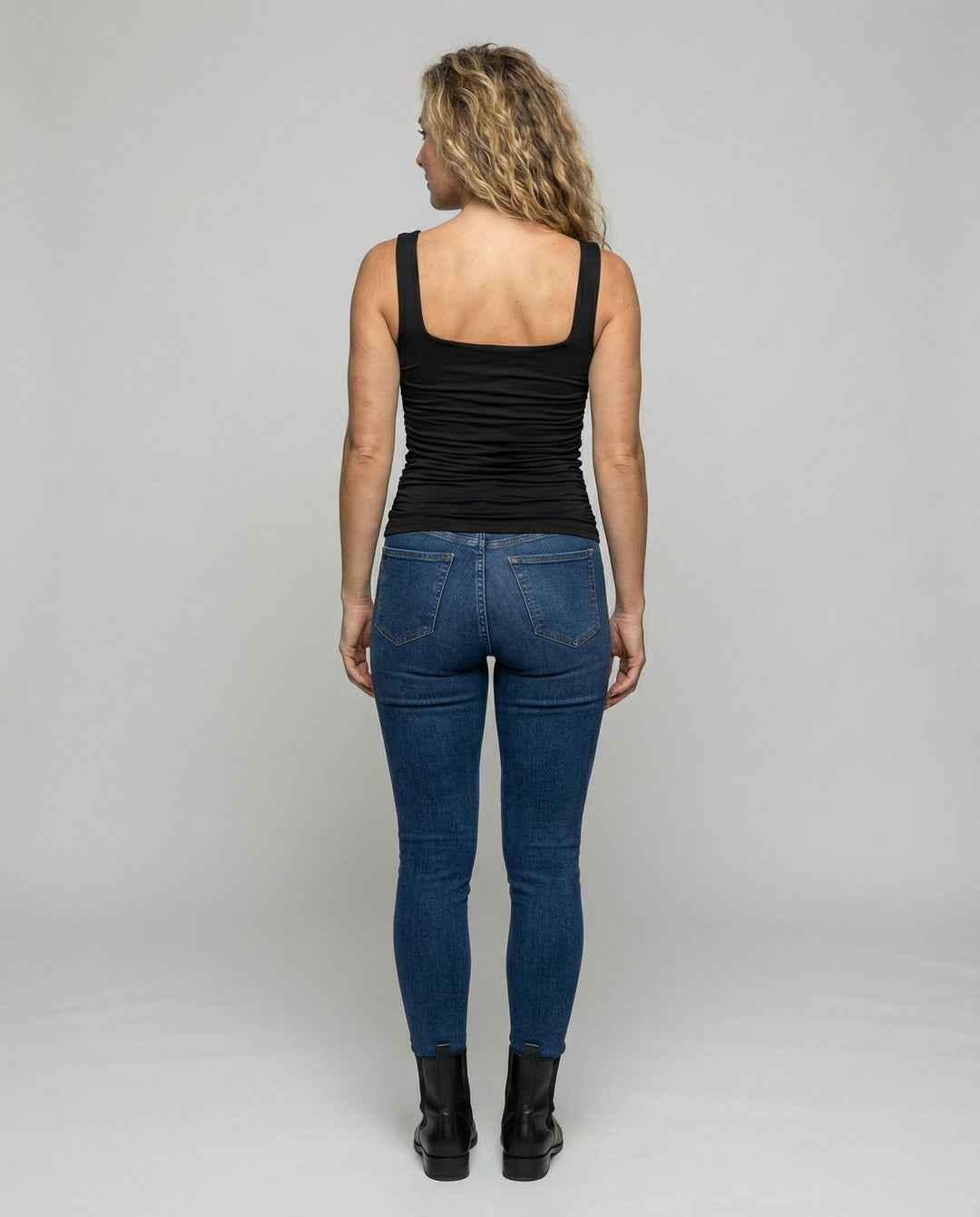 Woman in a figure-hugging casual top on a plain background.