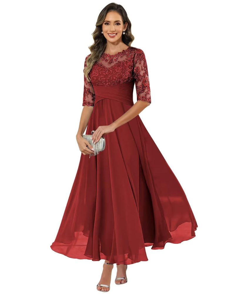 Female model wearing a long lace and chiffon evening dress on a plain background.