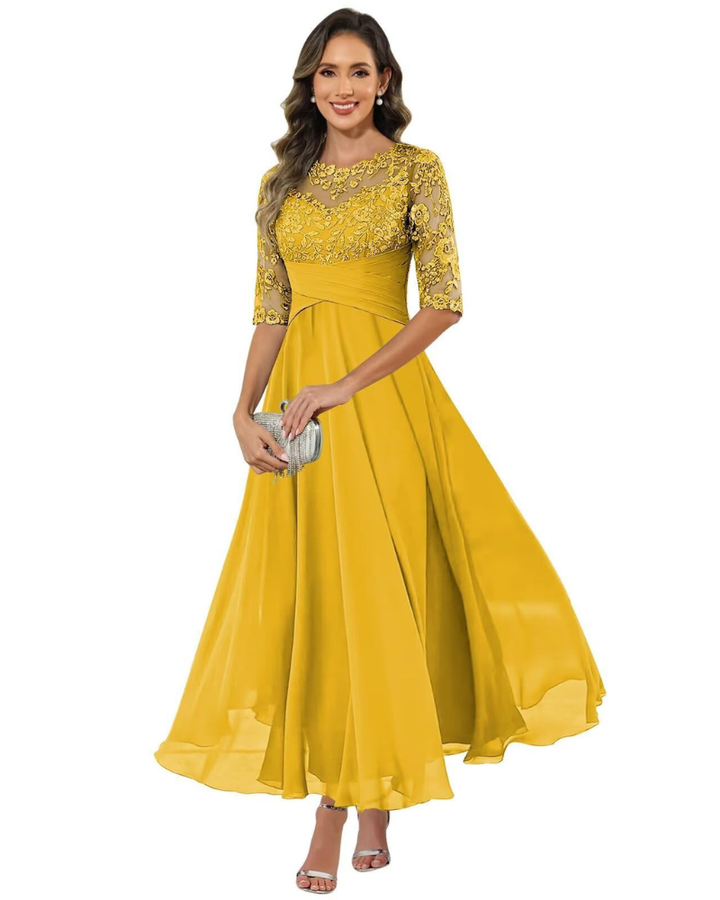 Woman wearing a long event dress with refined sleeve detail on a plain background.