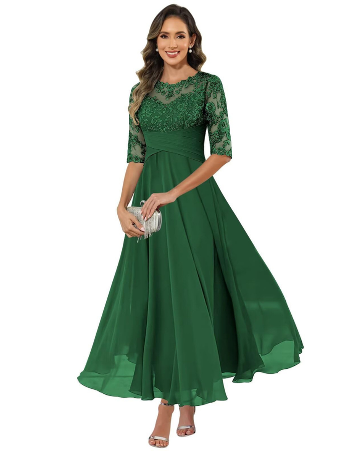 Female model wearing a long formal dress with lace overlay on a plain background.