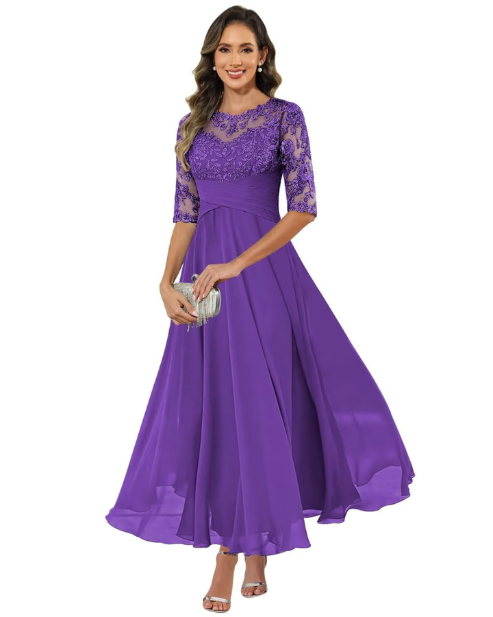 Woman in a long A-line evening dress with 3/4 sleeves on a plain background.