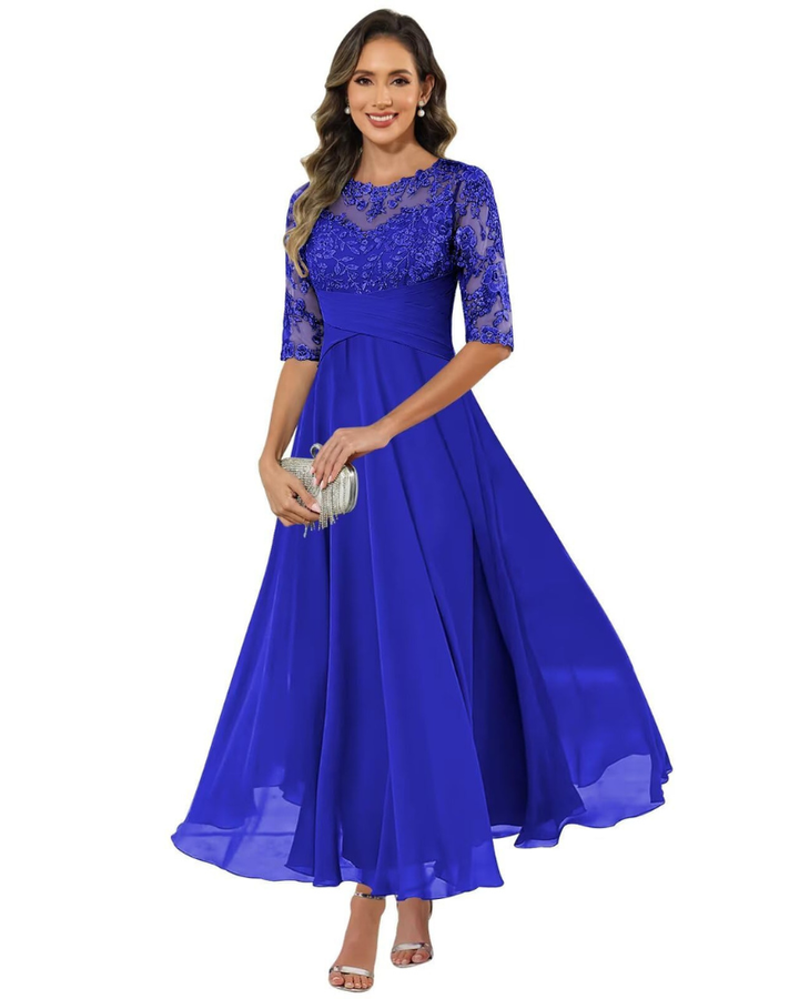 Model wearing a flowing formal dress with lace detail on a plain background.