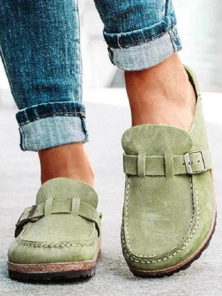 Woman wearing slip-on clogs on a plain background for casual everyday styling.