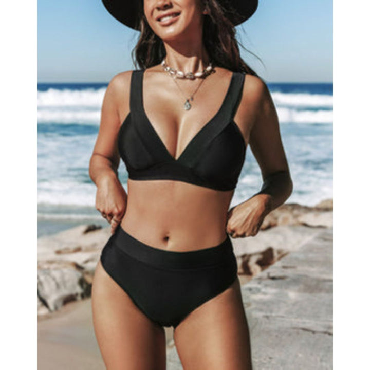 Woman displaying a flattering high-waist swimwear style on a beach background.
