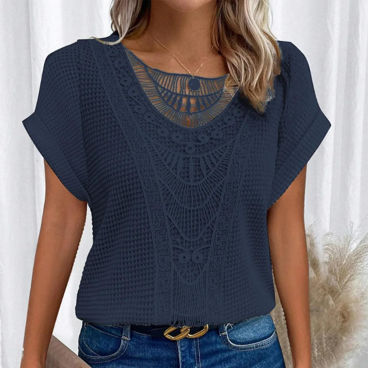  Female in a flattering lace top against a plain background.