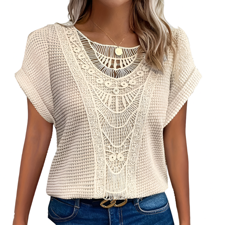 Woman wearing a lightweight lace top against a plain background.